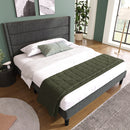 Bedroom with a bed featuring a green blanket and gray headboard.