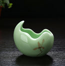 Green ceramic teapot with a dragonfly design on a dark surface