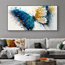 Colorful butterfly painting on a gray wall above a gray sofa with decorative pillows.