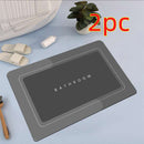 Mat, comforters, grey bathmat with 'Bathroom' text on a light blue surface, accompanied by slippers and a plant.