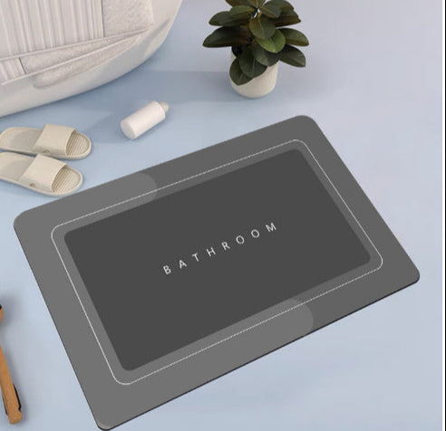 Mat, comforters, grey bathmat with 'Bathroom' text on a light blue surface with slippers and a plant.