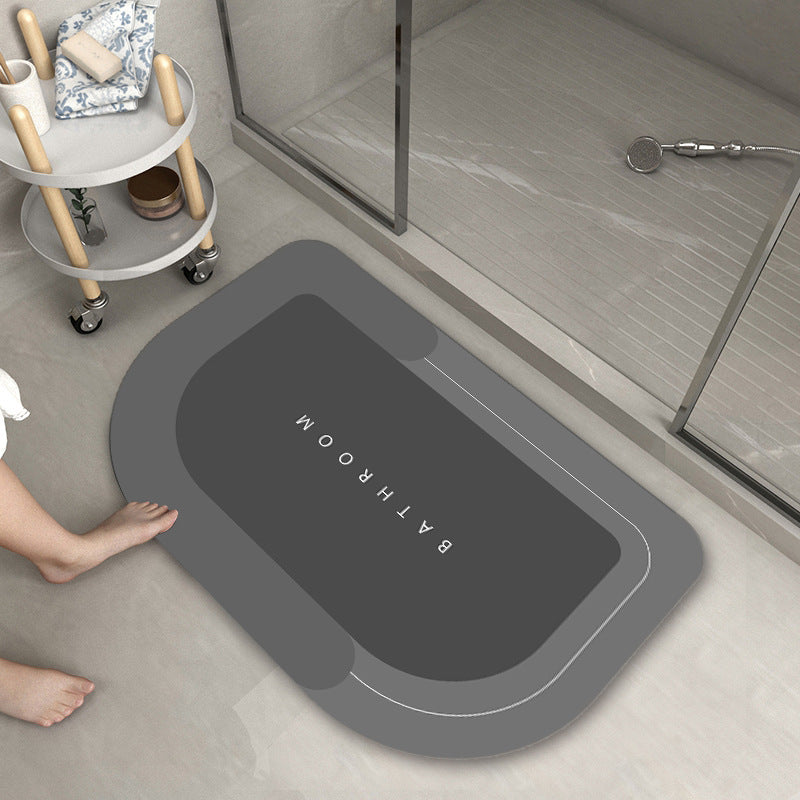 Mat, comforters, Gray bathmat with 'Bathroom' text on a bathroom floor.