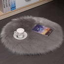 Mats, bed sheets, comforters, round grey fur rug with a cup, saucer, and book on a dark floor.