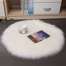Mats, bed sheets, comforters, round white fur rug on a dark floor with a bookshelf in the background