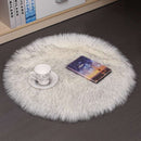 Mats, bed sheets, comforters, round white fluffy rug on a dark floor with a cup, saucer, and book on top.