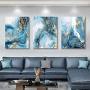 Home decor, room decor, wall decor, Three abstract art pieces in blue and gold on a wall above a grey sectional sofa.