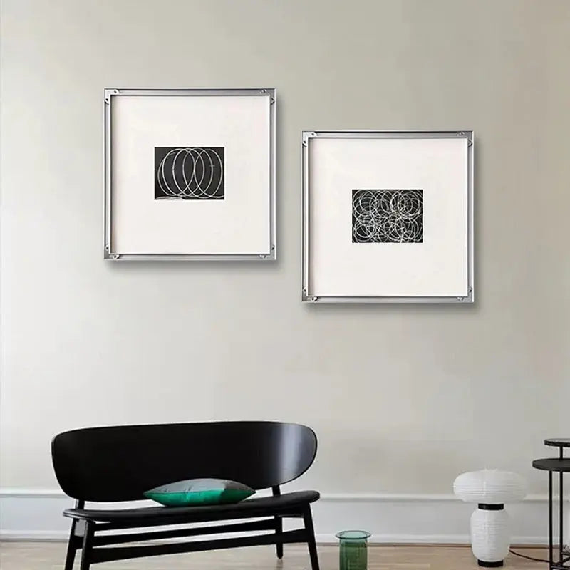 Home decor, wall decor, room decor, Two framed abstract artworks on a wall above a black sofa in a living room.