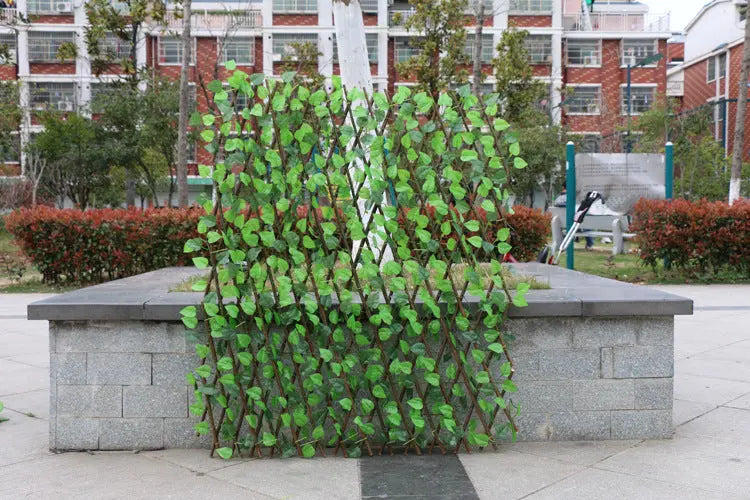 Garden pots, outdoor decor, garden ornaments, Green artificial hedge panel on a stone pedestal in an outdoor setting with buildings in the background