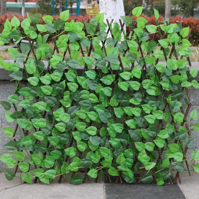 Garden pots, outdoor decor, garden ornaments, Artificial green leafy screen with wooden stakes on a concrete surface.